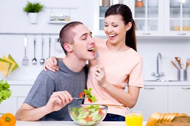 η κοπέλα τροφοδοτεί τον άνδρα με σαλάτα βιταμινών για δραστικότητα